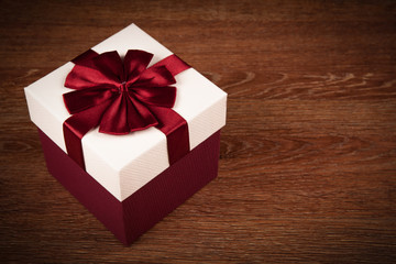 white box with red bow on a wooden background