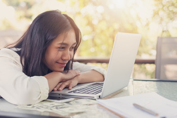 Online worker concept, Asian women smiling and using laptops  with the dollar on the desk