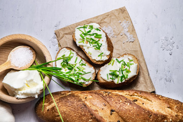 Small pieces of bread with curd spread decorated by green fresh chive background flat lay