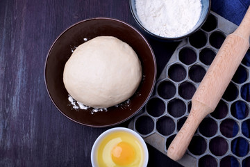 Dough and utensils for making dumplings against the dark background