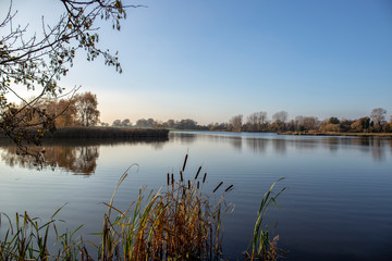 Obraz na płótnie Canvas Early morning at a lake with blue sky in Cheshire England UK
