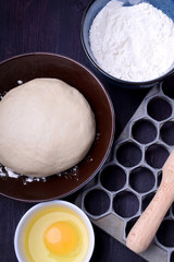 Dough and utensils for making dumplings against the dark background