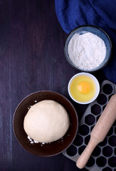 Dough and utensils for making dumplings against the dark background