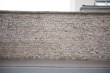 A beautifully built sea stone beach pebble concrete wall on  a seaside town street. beach seaside chic design. seaside walls. beach textured seaside feel.