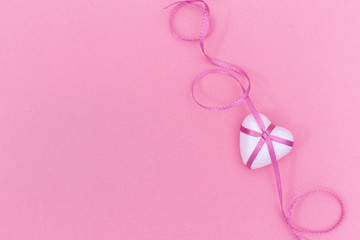    Love concept. White Heart and pink ribbon on pink paper background.