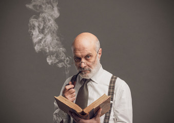 Senior academic professor reading and smoking a pipe