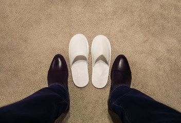 a man changes his shoes, takes off his shoes, he wears white slippers