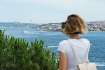 Fototapeta na wymiar Traveler smartphone, landscape photography. Attractive girl takes a story on her smartphone while traveling Istanbul, Turkey. 