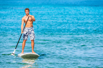 Paddle board stand up sup paddleboard man athlete paddling through blue ocean water background...