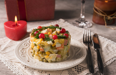 Russian salad on a white plate and cutlery on the table.