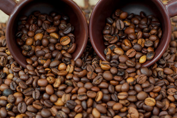 Coffee beans. Brown cups with roasted coffee beans. Grain coffee on burlap.