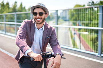 Fototapeta na wymiar Portrait of stylish man on electric scooter during sunny day