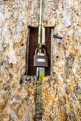 Abandoned building, with a fiberboard gate closed with a padlock in the foreground - focus on the padlock