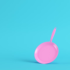 Pink frying pan on bright blue background in pastel colors