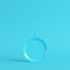 Frying pan on bright blue background in pastel colors