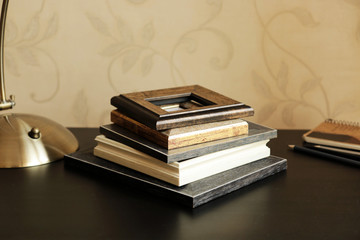 A stack of wooden frame, a notebook and  pencils on the desk