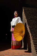 Femme, ombrelle jaune et mur en brique ancien Wat Umong