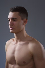 Beautiful young European athletic with bare torso, nice abs and muscles on white and gray background