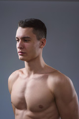 Fototapeta premium Beautiful young European athletic with bare torso, nice abs and muscles on white and gray background