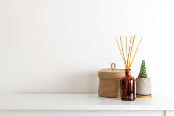 Scandinavian nordic hygge style, home interior - candle, scent aroma diffuser, small straw basket,...