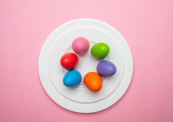 Easter eggs, pastel colors painted in a white plate, pink color background
