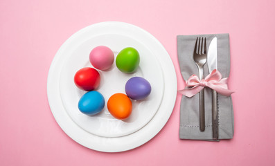 Easter eggs, pastel colors painted in a white plate, pink color background