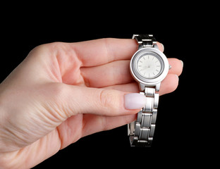 Female silver wrist mechanical watch in hand on a black background isolation