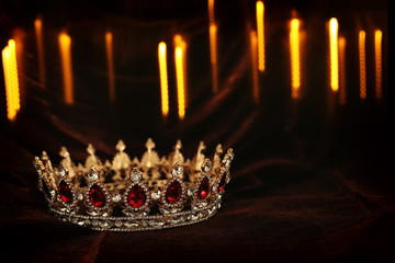 photo of gold crown over gothic dark silk background. Medieval period concept.
