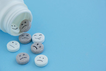 Pills medical. With painted faces and no pictures. Pills of joy, sadness,dead and indifference on blue background close-up