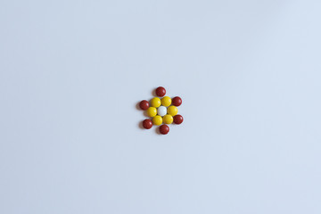 Colorful m m candy laid out in the shape of a floral mosaic isolated on white background....