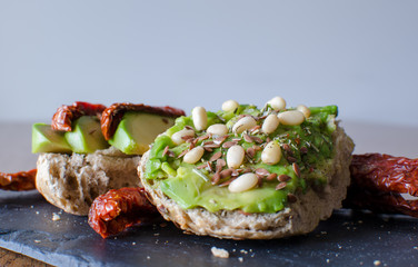 Avocado toast with dried tomatoes, pine nuts and flaxseeds. Close up. side view