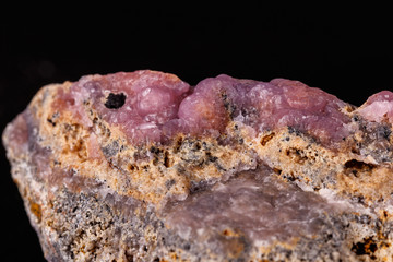 Macro pink Smithsonite mineral stone on microcline on black background