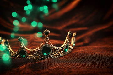 photo of gold crown over gothic dark silk background. Medieval period concept.