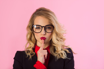 beautiful young girl in a black jacket with a crown on her head on a pink background