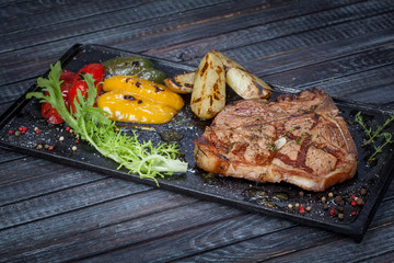  juicy, fried, tender steak with vegetables and sauces on a special stand