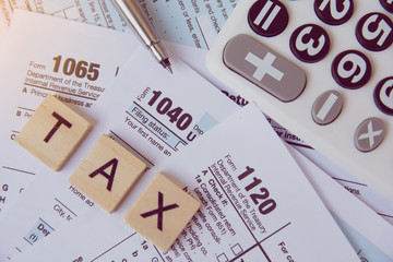 Tax season with wooden alphabet blocks, calculator, pen on 1040 tax form backgrounda