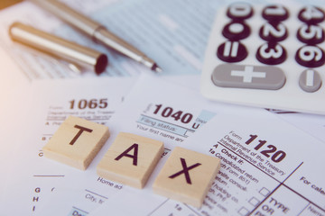Tax season with wooden alphabet blocks, calculator, pen on 1040 tax form backgrounda - obrazy, fototapety, plakaty