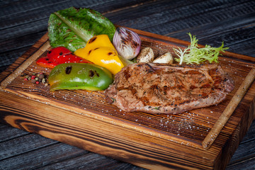  juicy, fried, tender steak with vegetables and sauces on a special stand