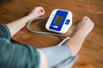 Woman health check blood pressure and heart rate at home with digital pressure, health and medical concept