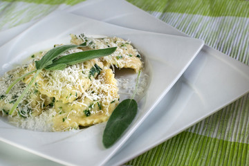 Italian pasta ravioli with ricotta, sage and spinaci on white plate.