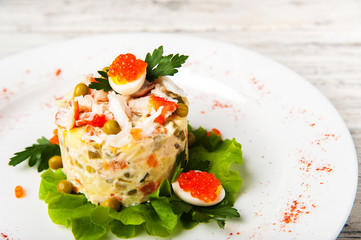 Salad Olivier with red caviar, chicken meat and beluga on a white plate. Traditional Russian cuisine, meat salad close-up and copy space.