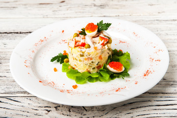 Salad Olivier with red caviar, chicken meat and beluga on a white plate. Traditional Russian cuisine, meat salad close-up and copy space.