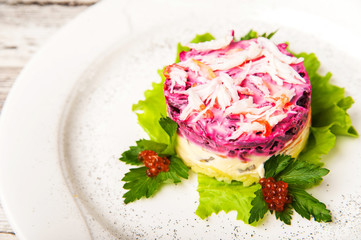 Herring salad under a fur coat with crabs on a white plate. Traditional Russian cuisine, herring under a fur coat close-up and copy space.