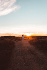 young woman jumping at sunset in the field