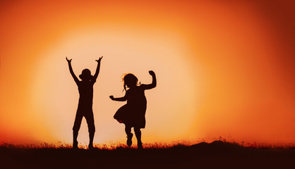 Obraz na płótnie Canvas Silhouette of happy children boys and girls jumping and dancing in sunset sky evening time background as successful, happiness and careless concept