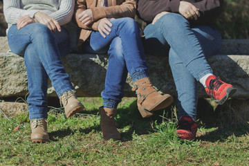 Mujeres sentadas con las piernas cruzadas sobre un banco de piedra con jeans
