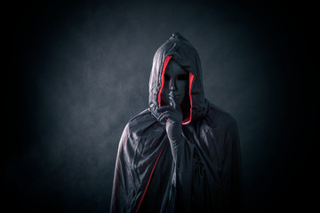 Scary figure with black mask in hooded cloak