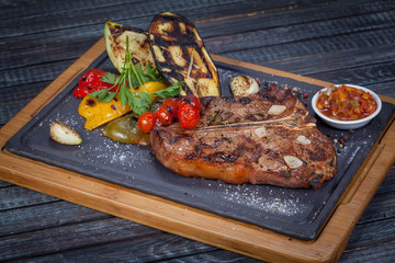  juicy, fried, tender steak with vegetables and sauces on a special stand