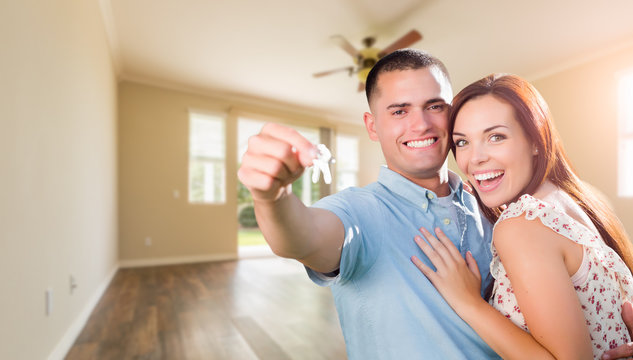 Young Military Couple with House Keys In Empty Room of New Home