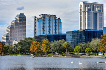 Orlando, Florida. December 24, 2018 Colorful buildings , autumn forest and swan boats in Eola Lake...